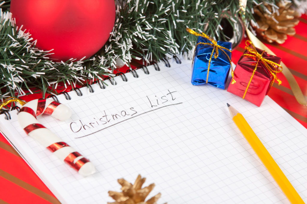 "Christmas List" written on paper surrounded by holiday decors