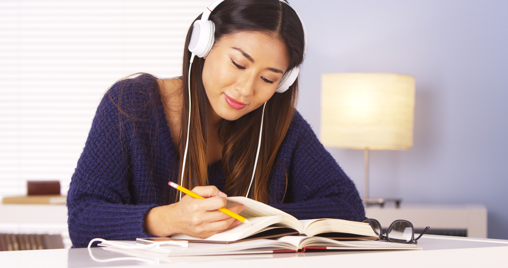 A young woman reading while wearing headphones