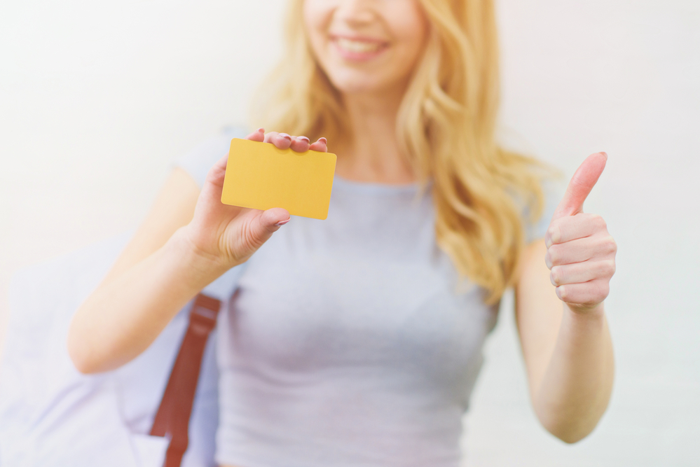 A young woman holding a card and giving a thumbs up