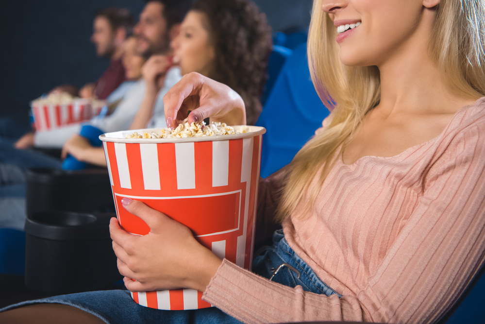 Friends sitting in a cinema while eating popcorn