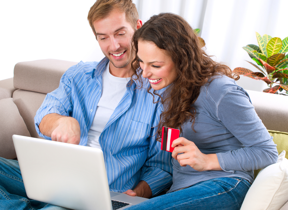 A couple with credit card smiling on a laptop