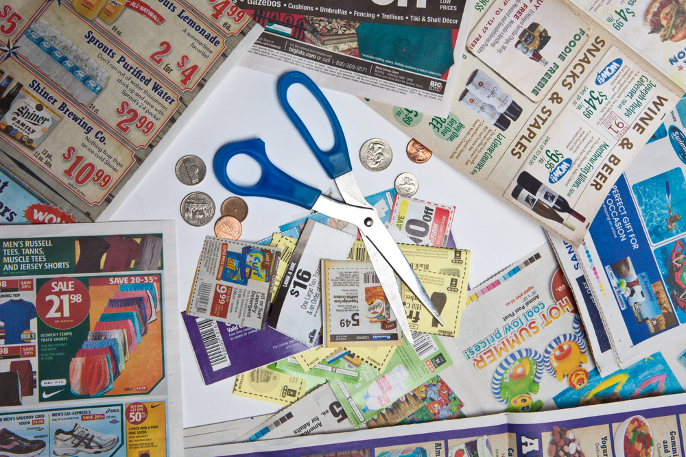 Coupons, a pair of scissors, and coins amid supermarket magazines