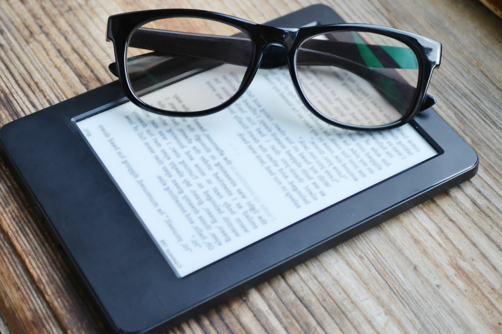 A pair of reading glasses sitting on a Kindle
