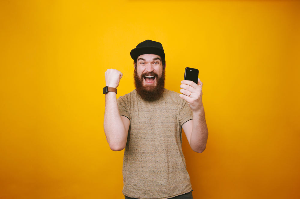 A happy man holding a fist and a phone