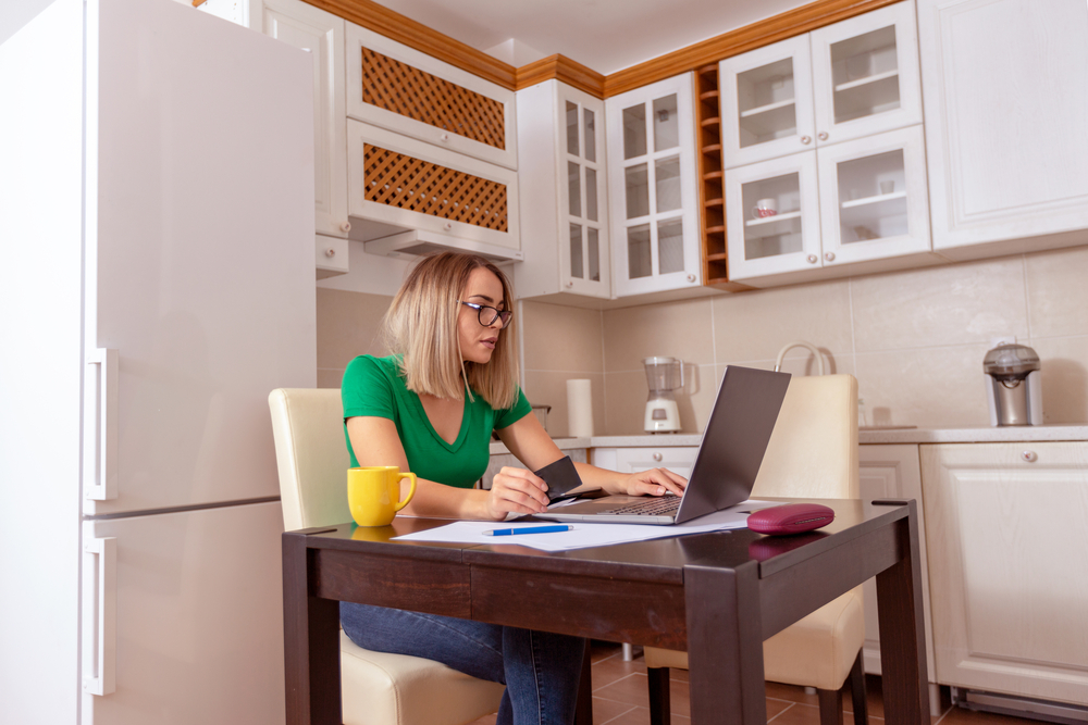 A woman sitting in the kitchen, on a laptop