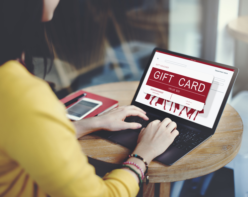 A woman on laptop with gift card flashed on screen