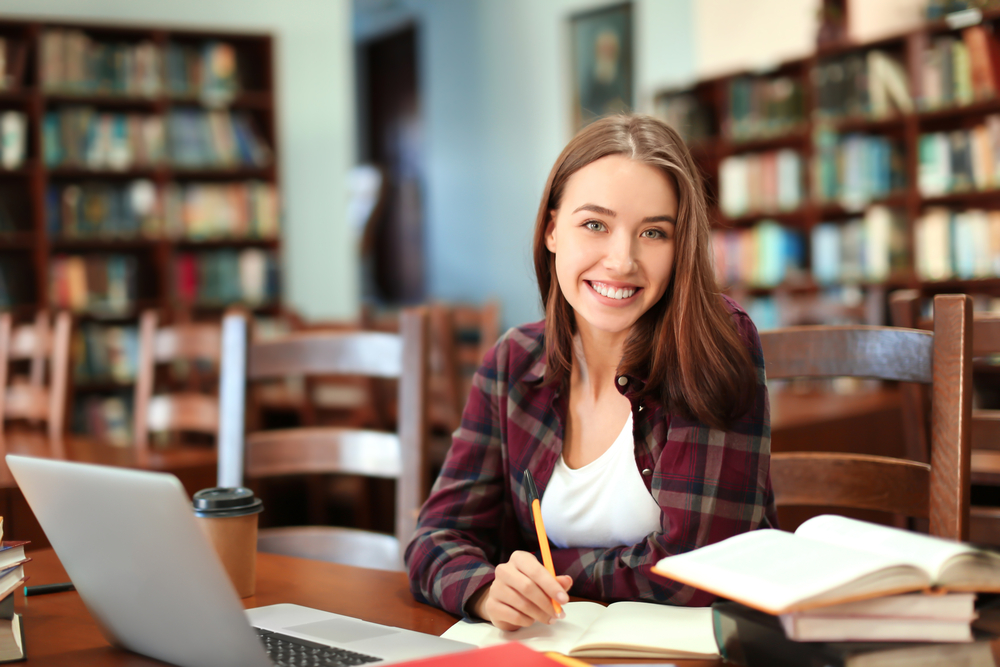 A smiling young woman studying in the library