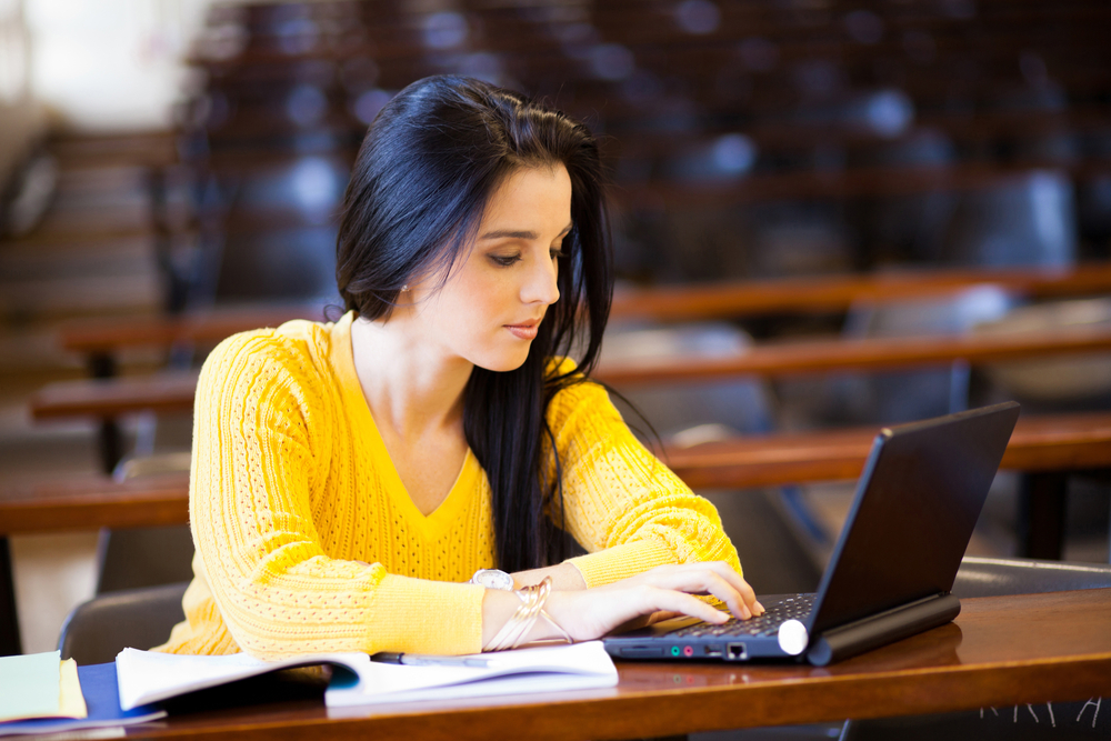 A young woman using a laptop in a classroom