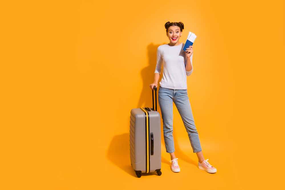 A young woman with a luggage and airplane tickets